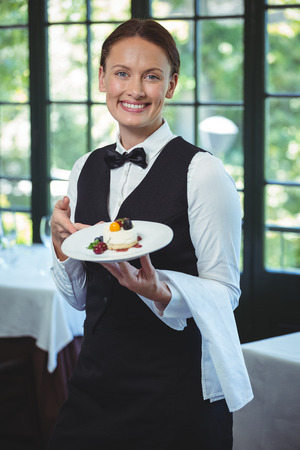 Smiling waitress holding a plate in a restaurantの写真素材