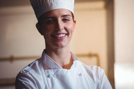 Chef smiling and posing with crossed arms in a commercial kitchenの写真素材