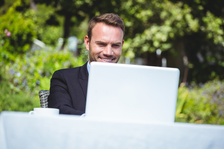 Smiling businessman using laptop and having a coffee in a restaurantの写真素材