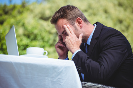 Nervous businessman working with laptop in a restaurantの写真素材