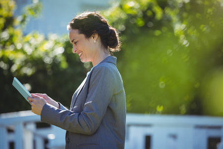 Pretty businesswoman using tablet outside on a terraceの写真素材