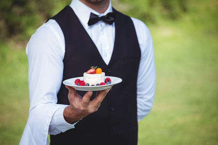 Handsome waiter holding a plate outsideの写真素材