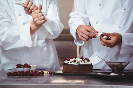 Chefs decorating a cake they just made in a restaurantの写真素材
