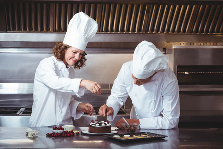 Chefs decorating a cake in a restaurantの写真素材