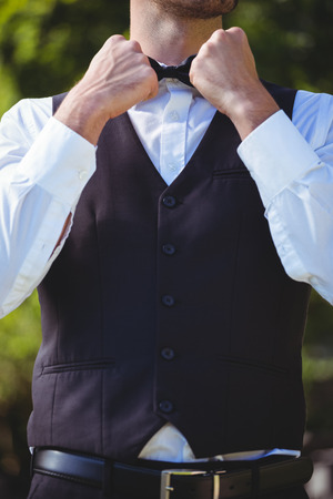 Handsome waiter reattaching his bow tie outsideの写真素材