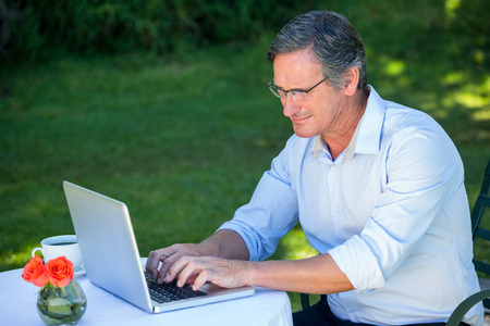 Casual businessman using laptop sitting on a terraceの写真素材