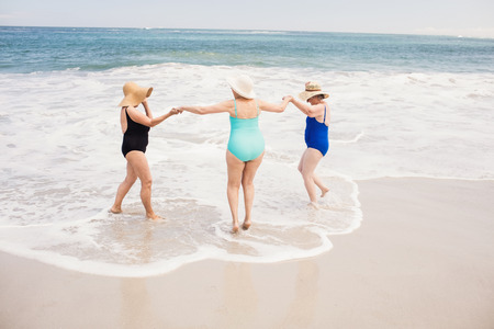 Senior woman friends playing in water at the beachの写真素材