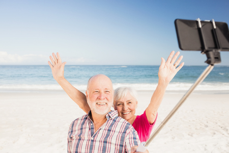 Senior couple taking selfie on the beachの写真素材
