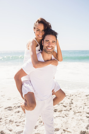 Boyfriend giving piggy back to girlfriend at the beachの写真素材