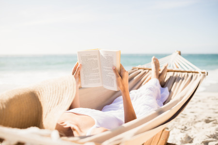 Woman reading book in hammock on the beachの写真素材
