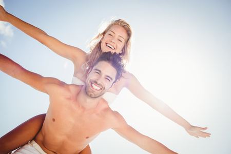 Boyfriend giving piggy back to girlfriend at the beachの写真素材