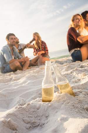 Smiling friends sitting on sand on the beachの写真素材