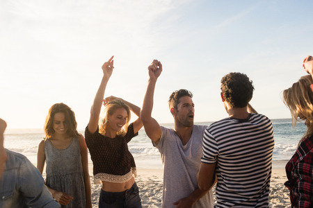 Happy friends dancing together on the beachの写真素材
