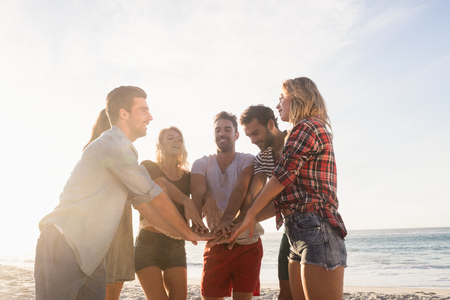 Happy friends gathering hands on the beachの写真素材