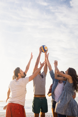 Happy friends playing beach volleyballの写真素材
