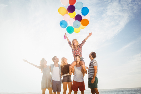 Portrait of friends holding balloon on a sunny dayの写真素材