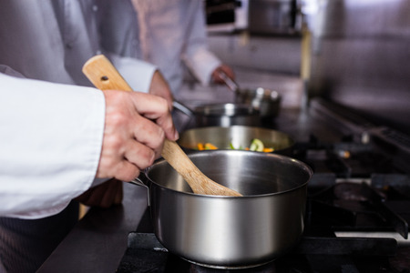 Close-up of chef preparing food in the kitchen of a restaurantの写真素材
