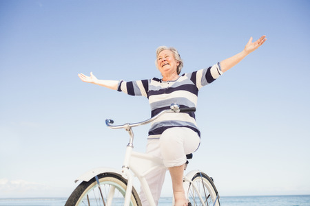 Senior woman on a bike on the beachの写真素材
