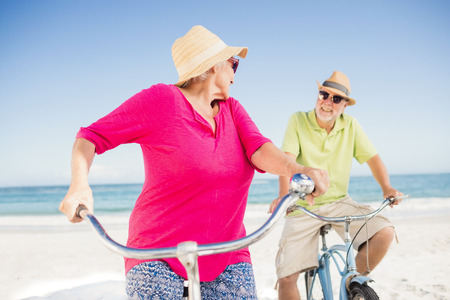 Senior couple going for a bike ride on the beachの写真素材