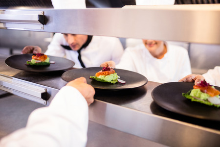 Chef keeping appetizer plate ready on the order station in the kitchen of a restaurant