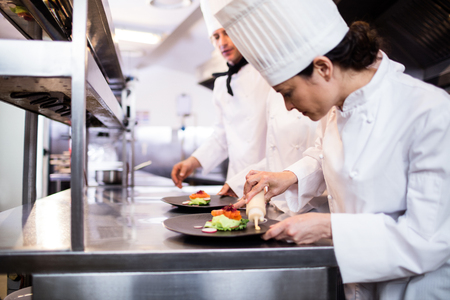 Chef decorating a food plate in the commercial kitchenの写真素材