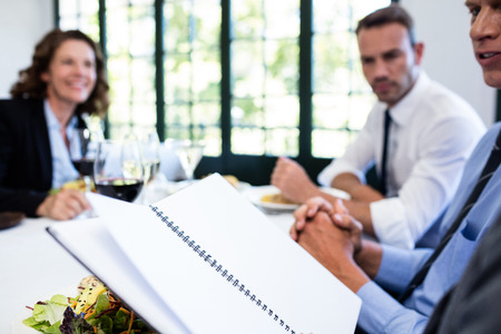 Business colleagues looking at a file and discussing in restaurantの写真素材