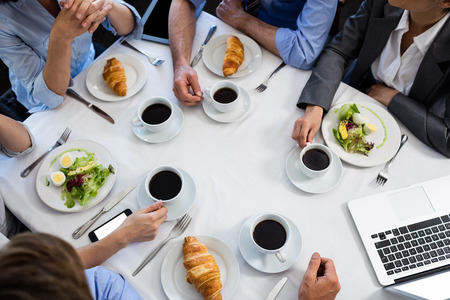 Coffee, croissant and salad on table in restaurant during business meetingの写真素材