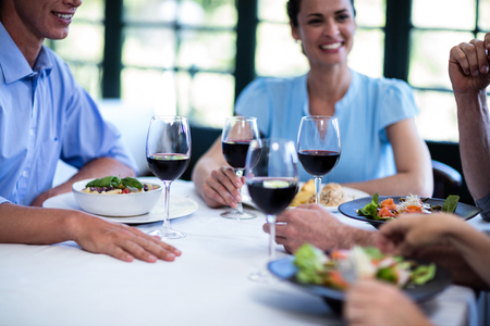 Young woman holding a wine glass while having lunch with friends in restaurantの写真素材