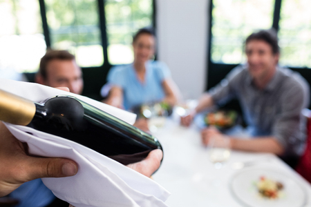 Close-up of waiter carrying a wine bottle in a restaurantの写真素材