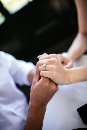 Close-up of couple holding hands with engagement ringの写真素材