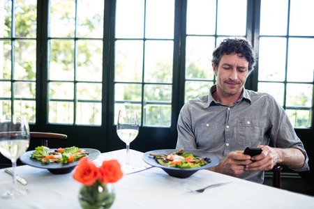 Man in a restaurant using mobile phone to type a text messageの写真素材