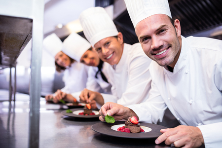 Portrait of chefs team finishing dessert plates in the kitchenの写真素材