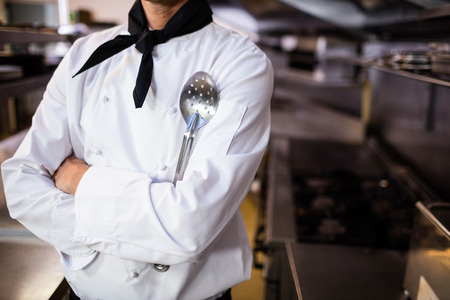 Chef standing with a spatula in the kitchenの写真素材