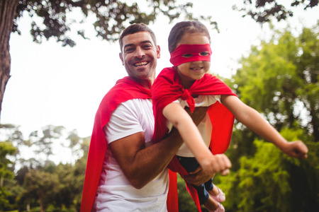 Father and daughter pretending to be a superhero in parkの写真素材