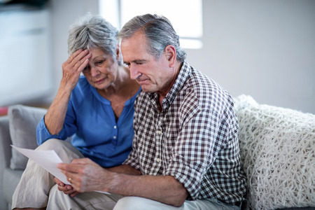 Worried senior couple checking the bills at homeの写真素材