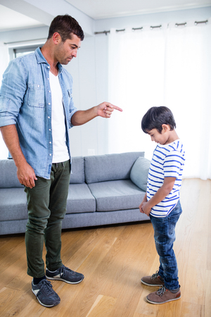Angry father scolding his son in living room at homeの写真素材