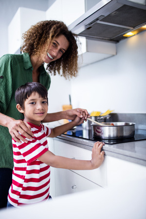 Portrait of mother and son cooking in kitchen at homeの写真素材