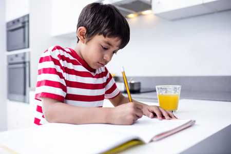 Portrait of boy doing homework in kitchen at homeの写真素材