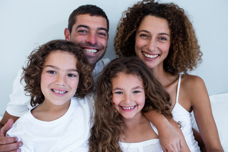 Portrait of family sitting together on bed at homeの写真素材