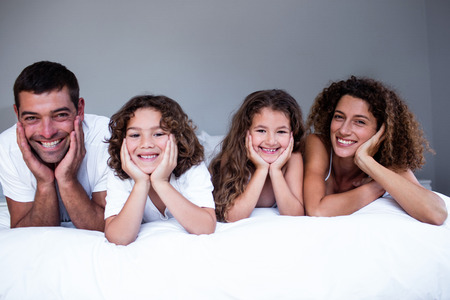 Portrait of happy family lying on bed in bedroom