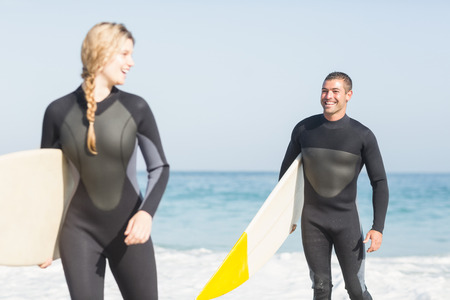 Couple with surfboard walking on the beach on a sunny dayの写真素材