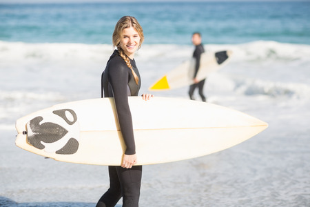 Surfer with a surfboard walking on the beach on a sunny dayの写真素材