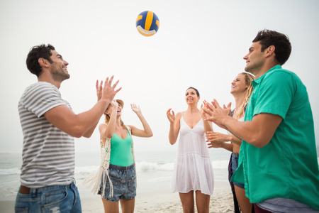 Group of friends playing with a beach ball on the beachの写真素材