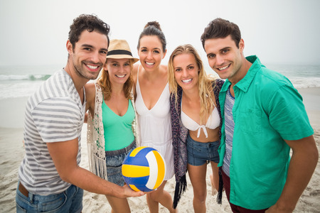 Group of friends with beach ball having fun on the beach on a sunny dayの写真素材