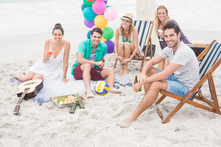 Group of friends with drinks having fun together on the beach on a sunny dayの写真素材