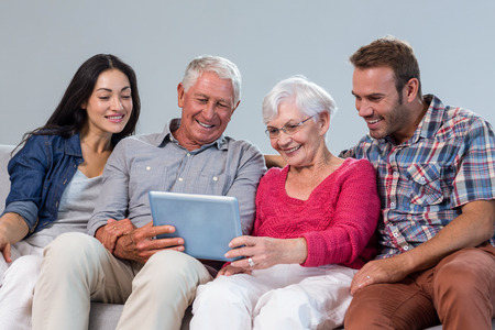 Happy family sitting on sofa using a digital tablet in living room