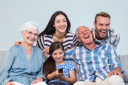 Happy family watching television sitting on a sofa in the living roomの写真素材