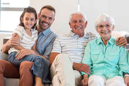 Portrait of happy family sitting on sofa in their living room