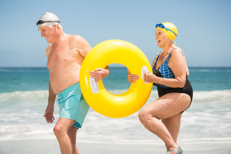 Senior couple with swimming ring at the beach on a sunny dayの写真素材