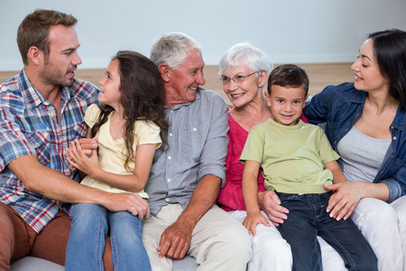 Family sitting on sofa and interacting with each other in living roomの写真素材